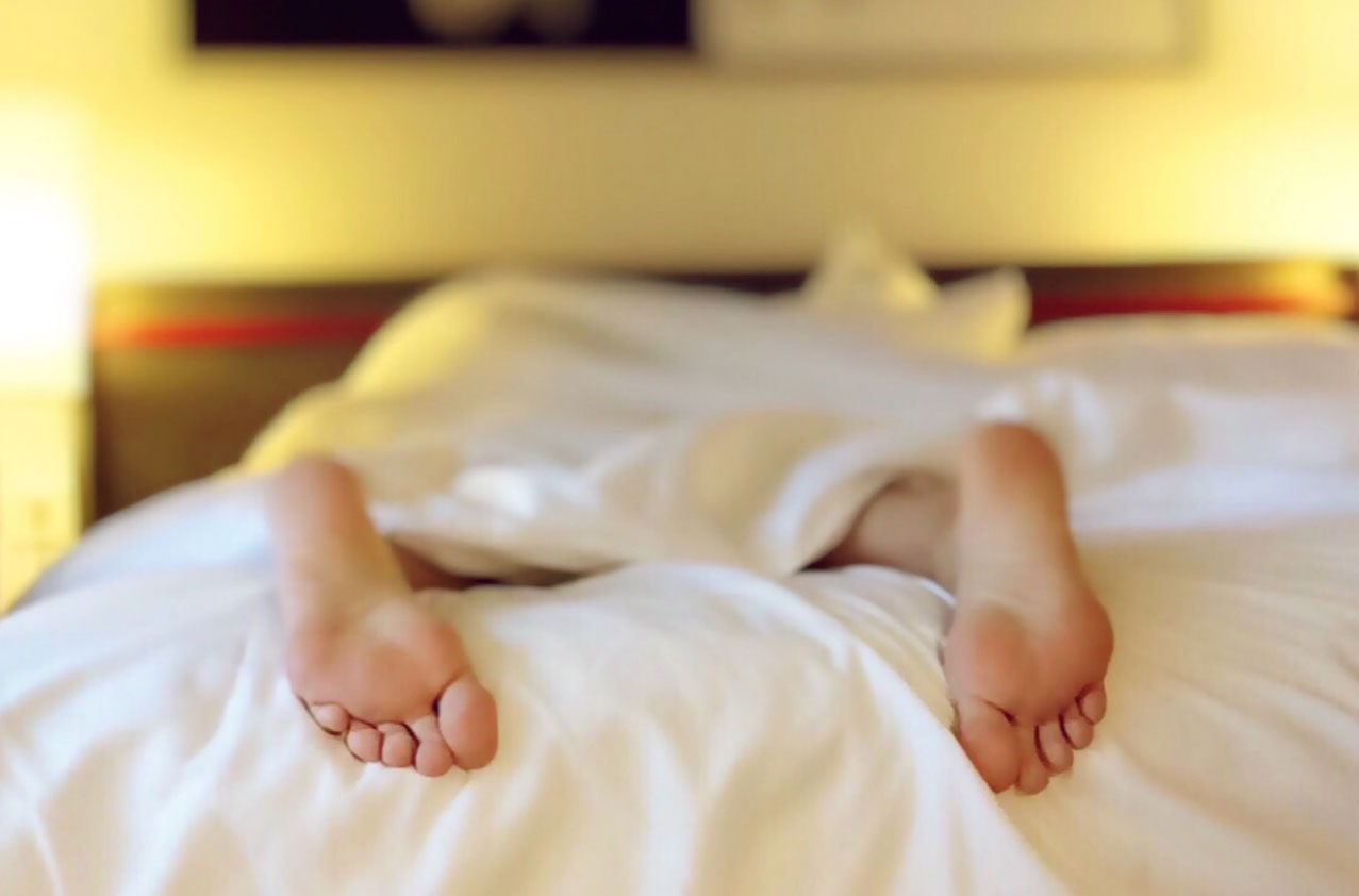 Photo foot sticking out from under the covers as a person is sleeping